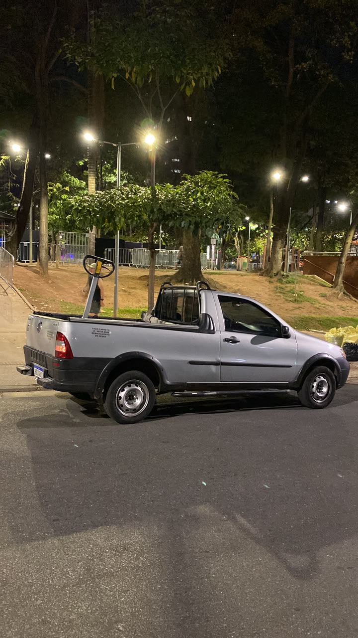 Strada prata da Pikeno estacionada à noite, perto de uma praça arborizada